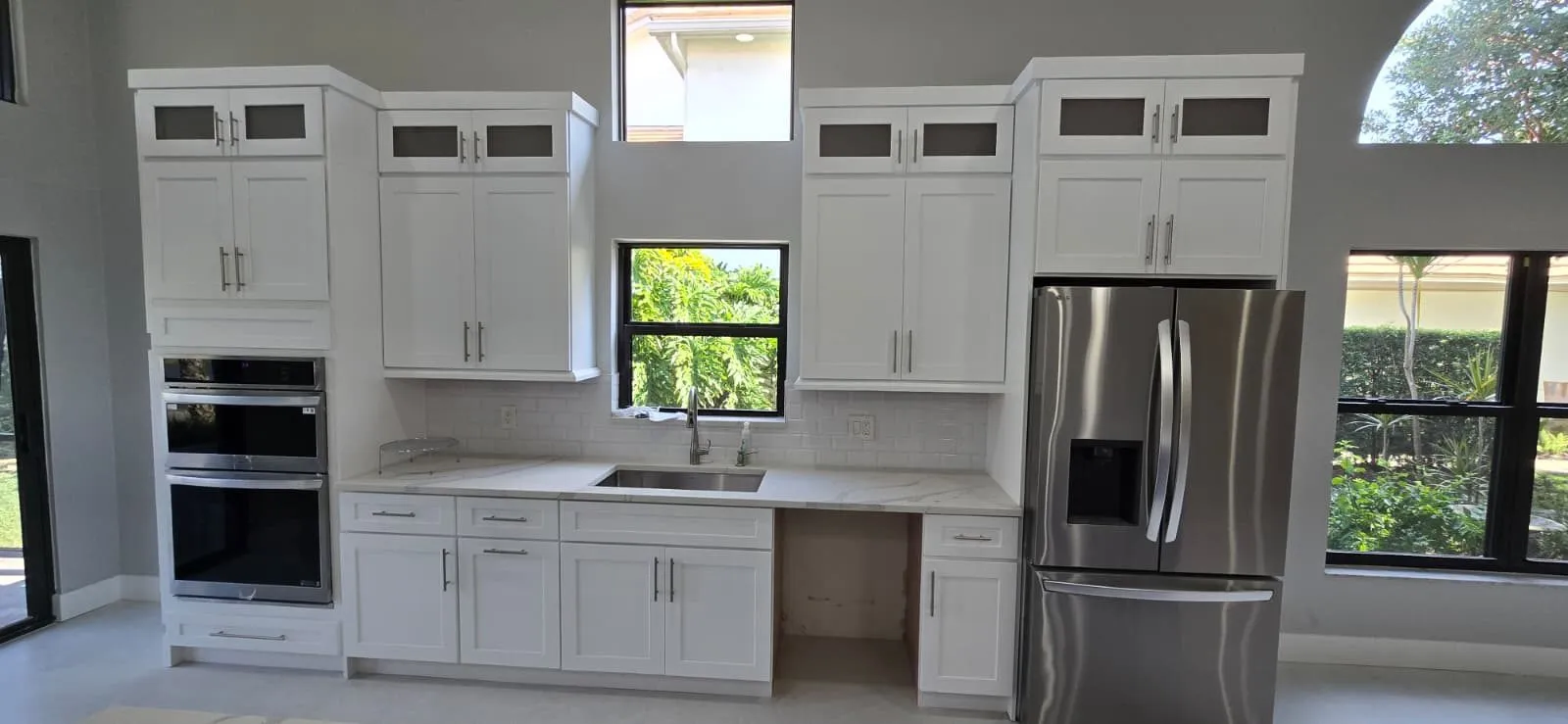 Finished white shaker kitchen with subway backsplash and stainless appliances